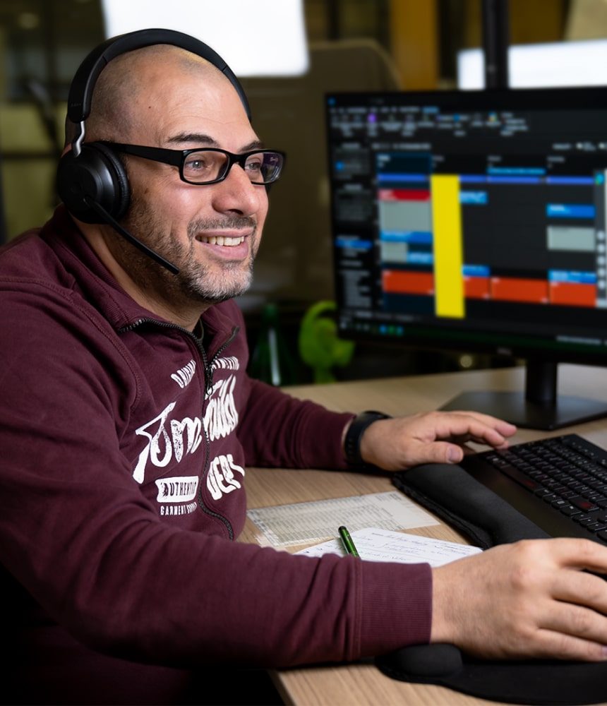Trading-Coach mit Headset am Arbeitsplatz erklärt am Bildschirm ein Daytrading-Demokonto.