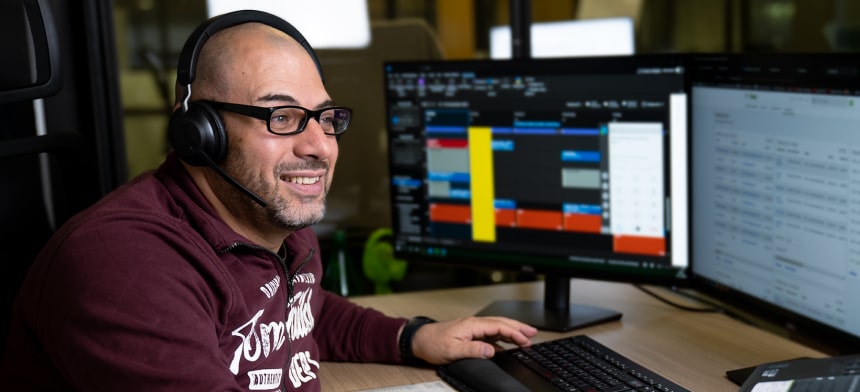 Trading-Coach mit Headset am Arbeitsplatz erklärt am Bildschirm ein Daytrading-Demokonto.