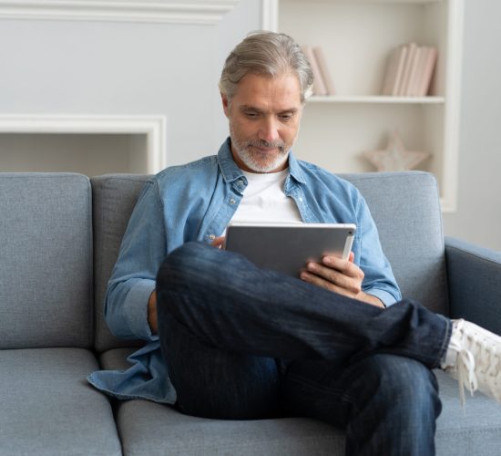 Handsome middle aged businessman is using a laptop and smiling while working at home